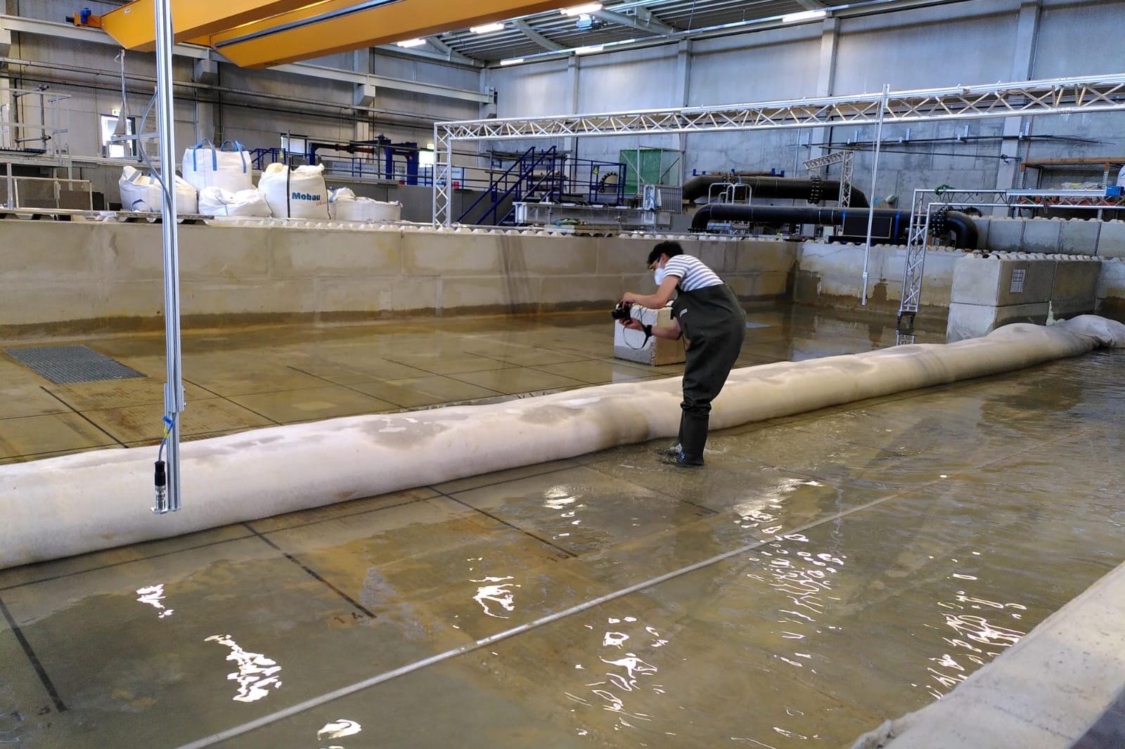 Es ist eine Halle von innen zu sehen. Eine Person steht auf dem wasserbedeckten Boden.