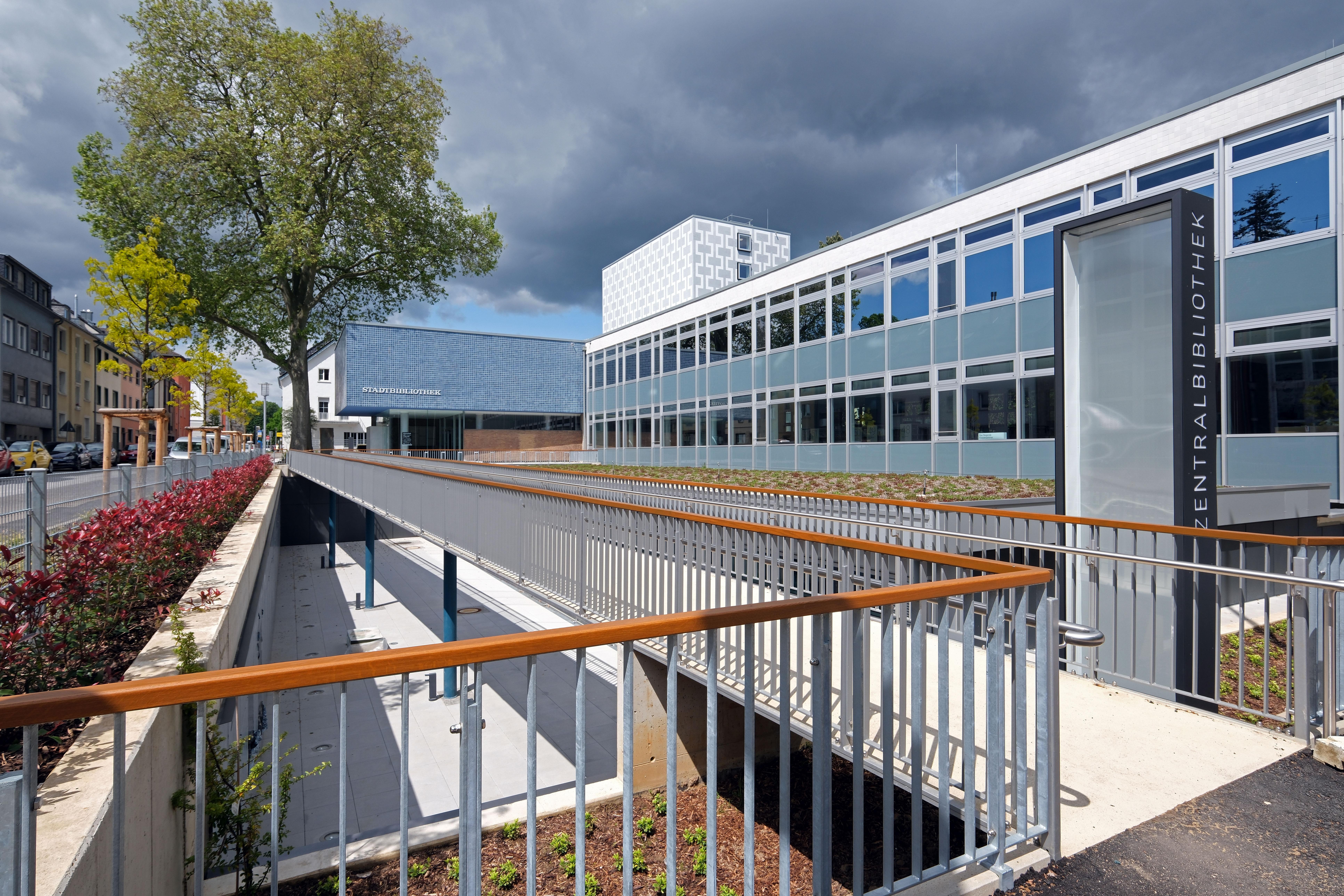 Es ist die Außenansicht derStadtbibilothek zu sehen. Das Gebäude hat viele Fenster.