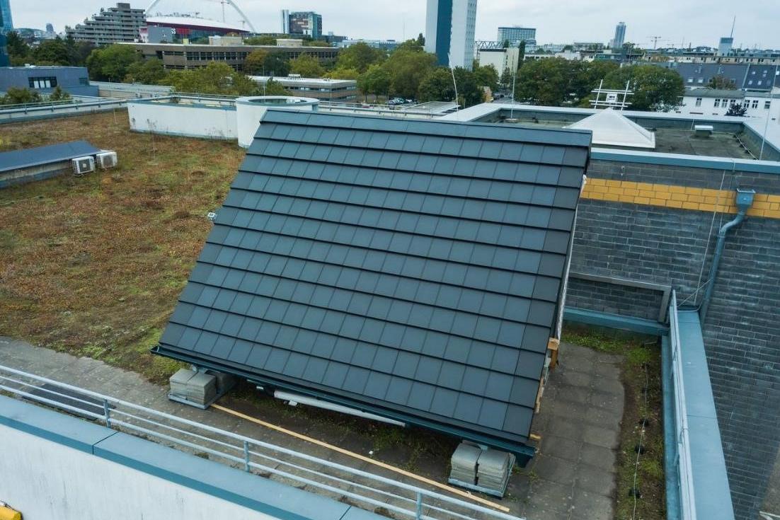 Ein Solarpanel auf einem Flachdach. Im Hintergrund ein Stadtpanorama.