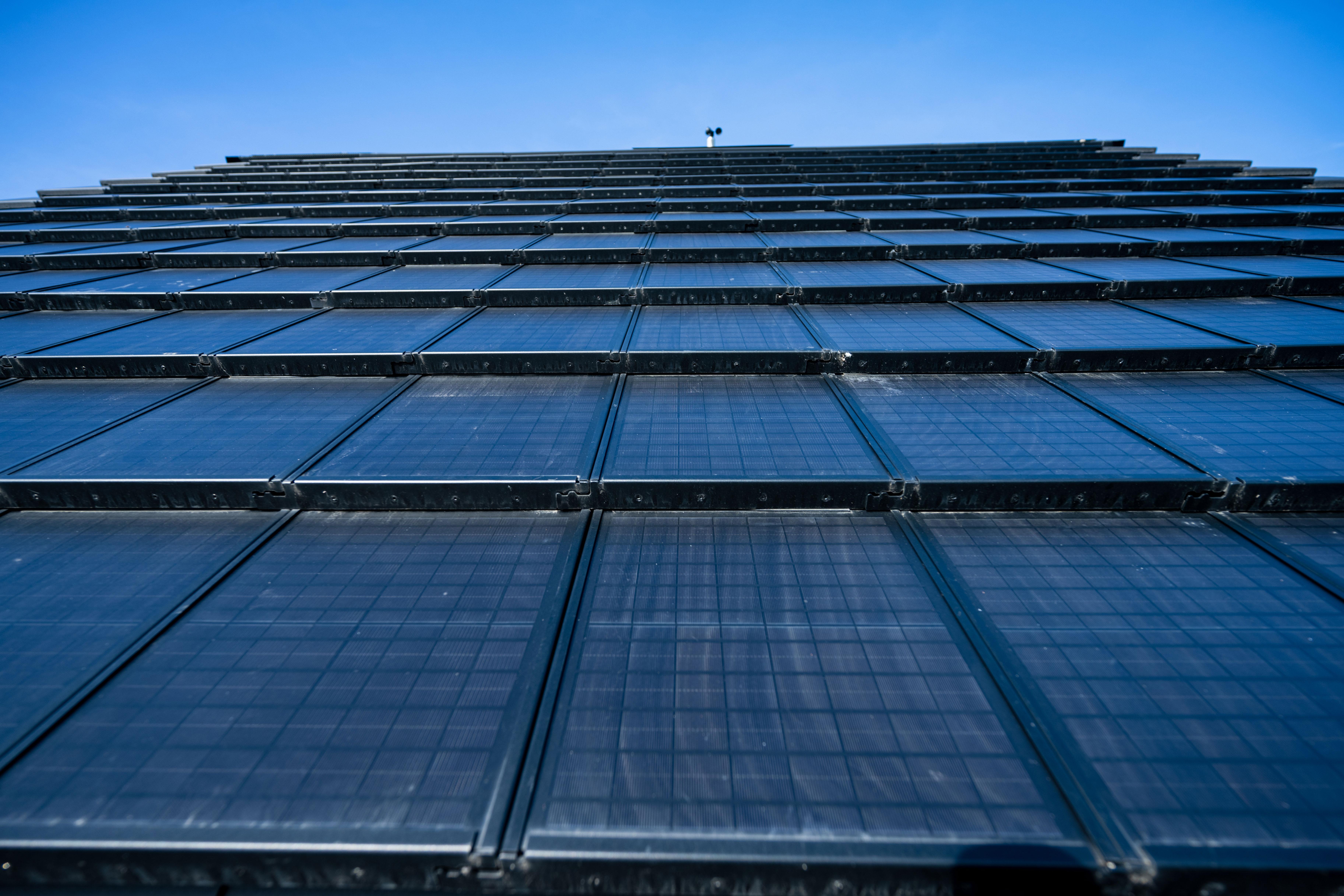 Eine mit Solarpanels gedeckte Wand ragt in einen blauen Himmel.