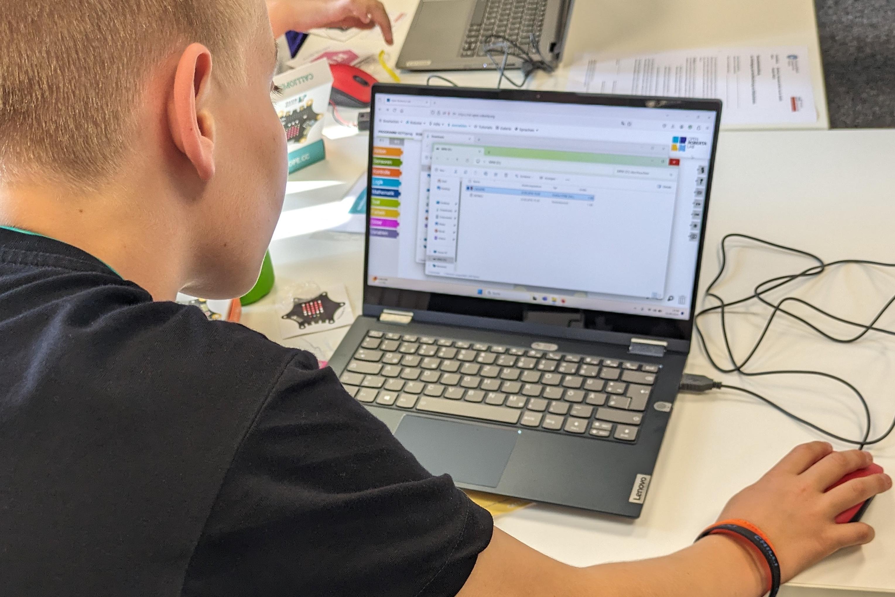 Ein Kind sitzt an einem Laptop und man schaut dem Kind über die Schultern.