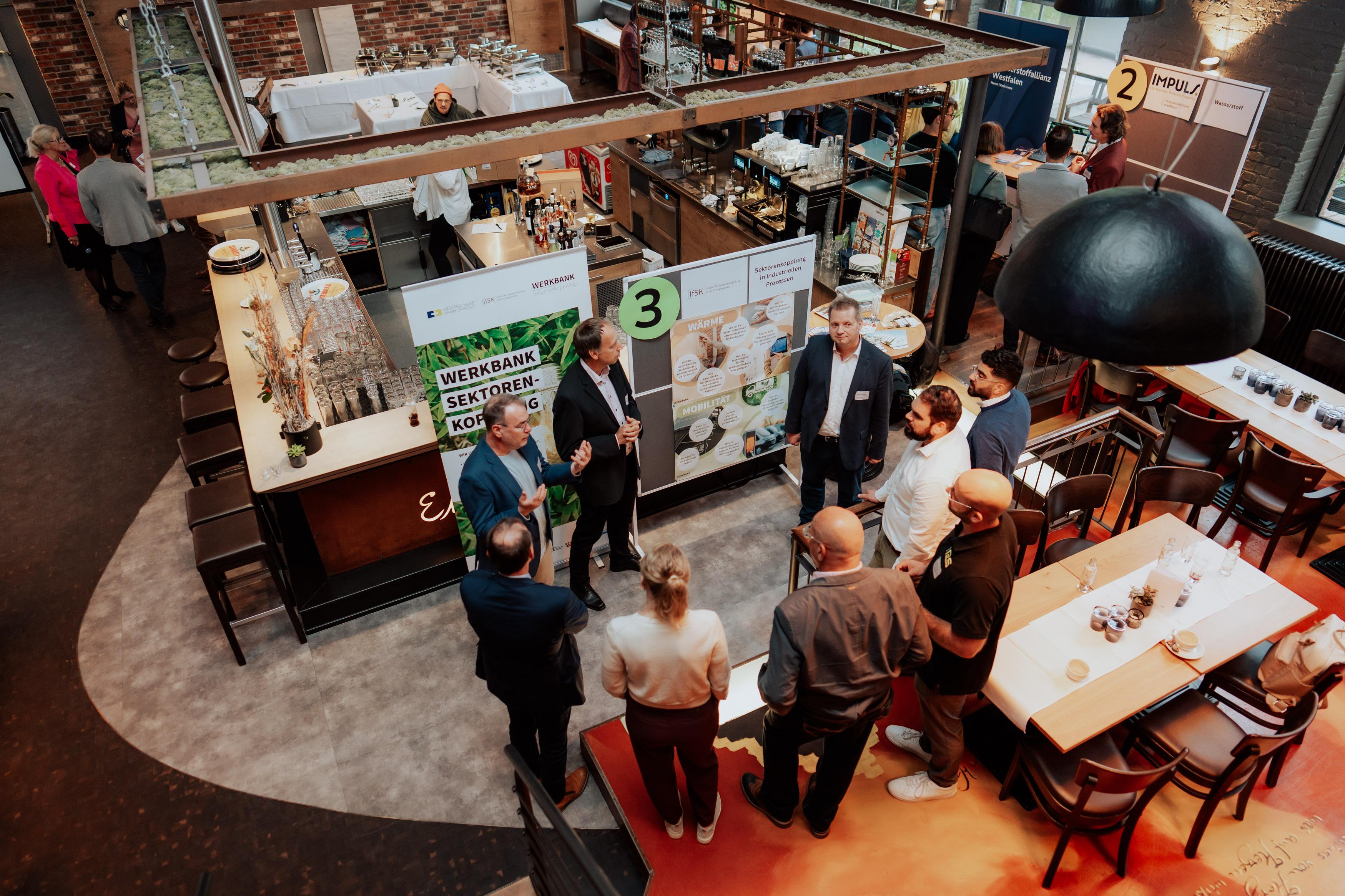 Gruppe von Menschen fotografiert von oben stehen in einem Kreis vor Planwänden. 