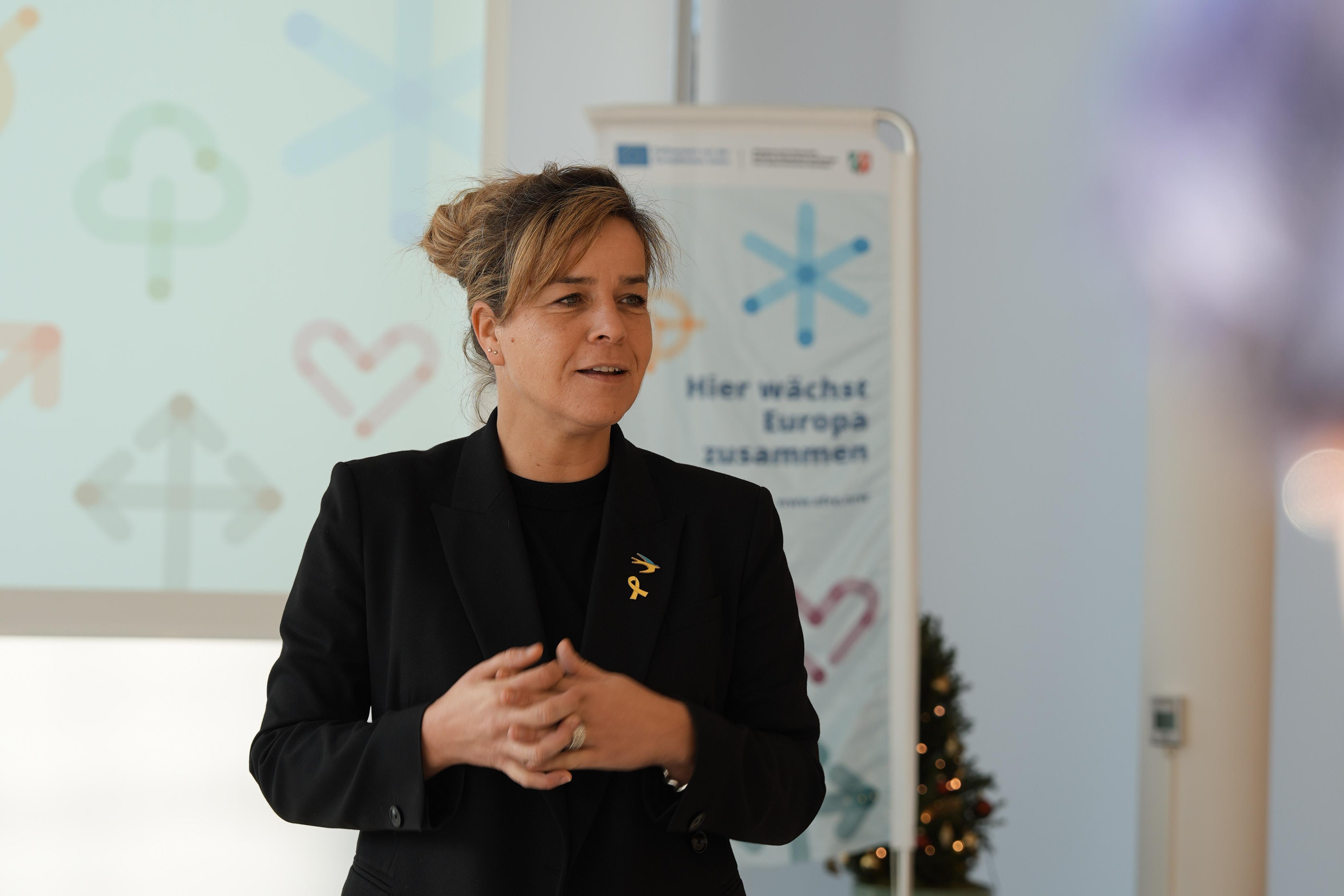 Frau Neubaur steht ein einem Stehtisch und hält eine Rede.