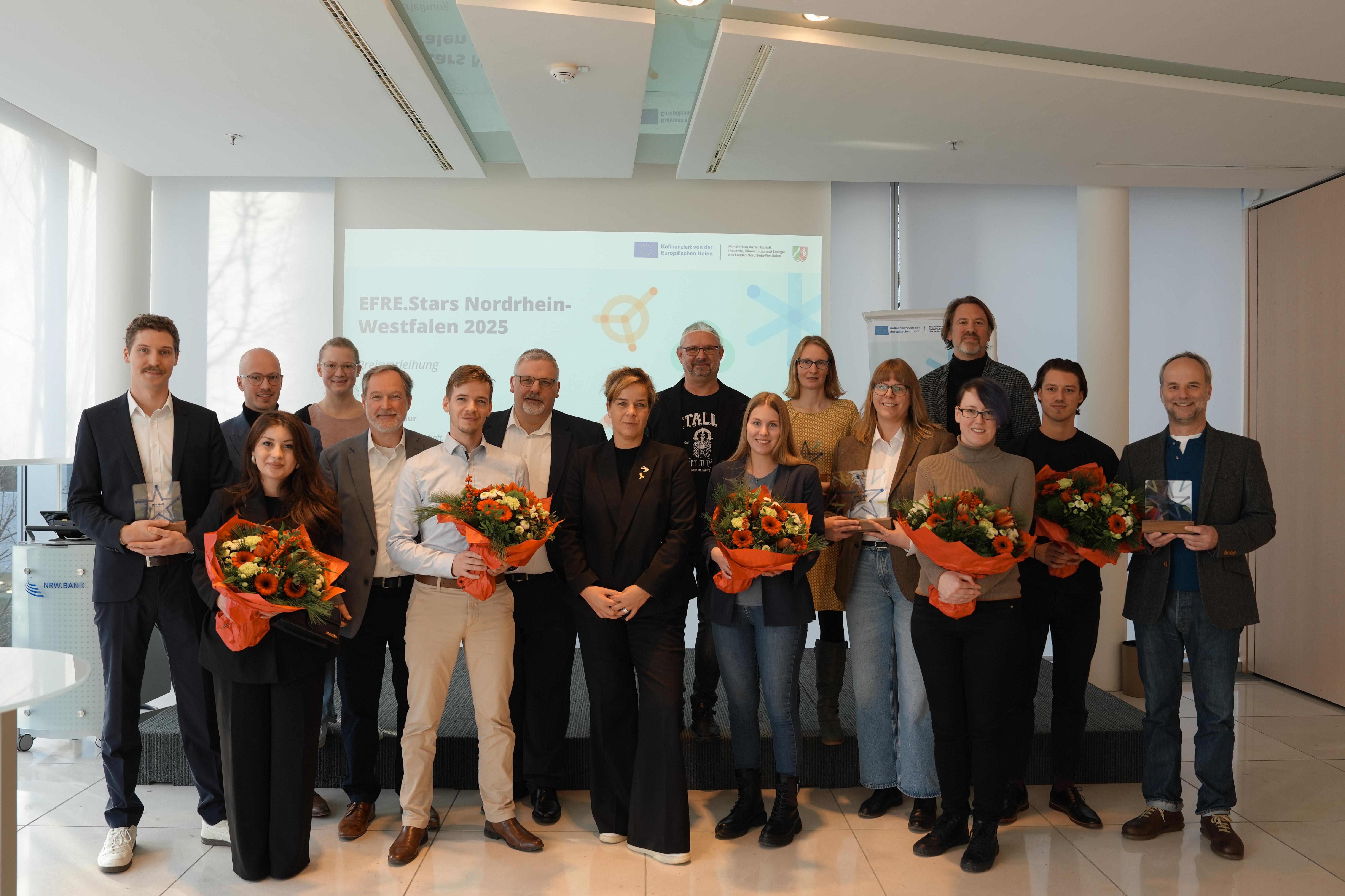 Viele Personen posieren für ein Gruppenbild und lächeln in die Kamera.