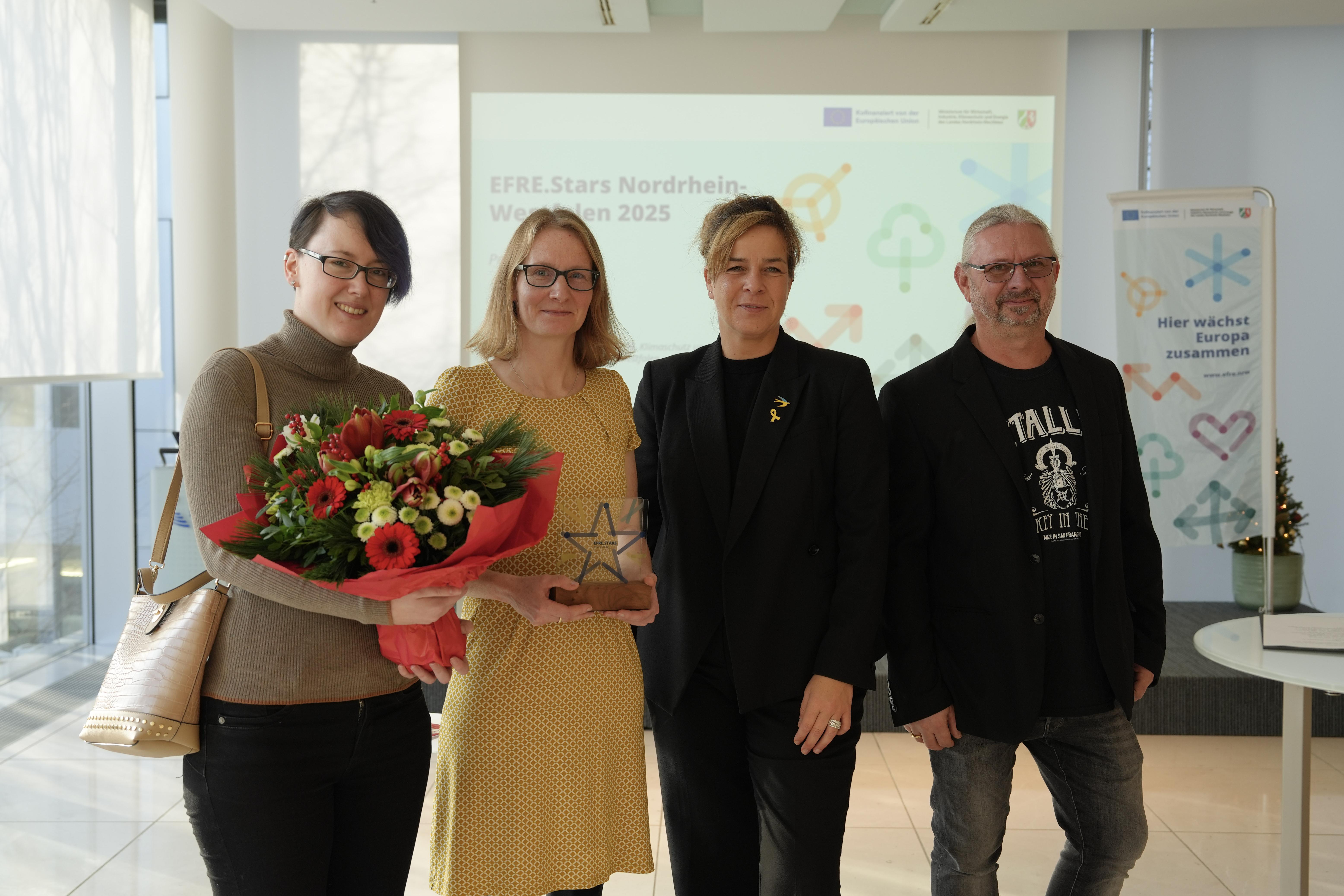 Vier Leute schauen lächelnd in die Kamera.