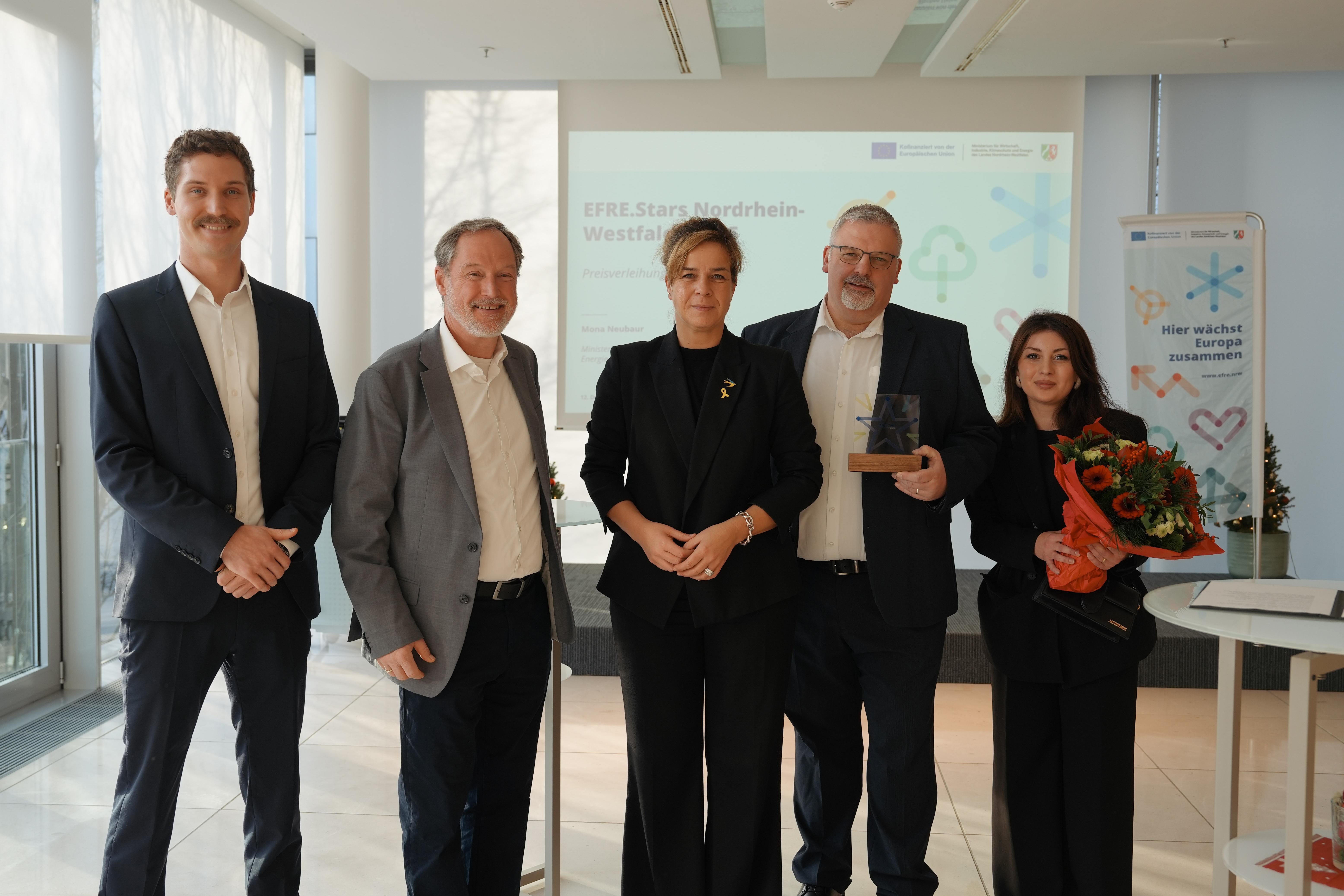 Fünf Leute schauen lächelnd in die Kamera.