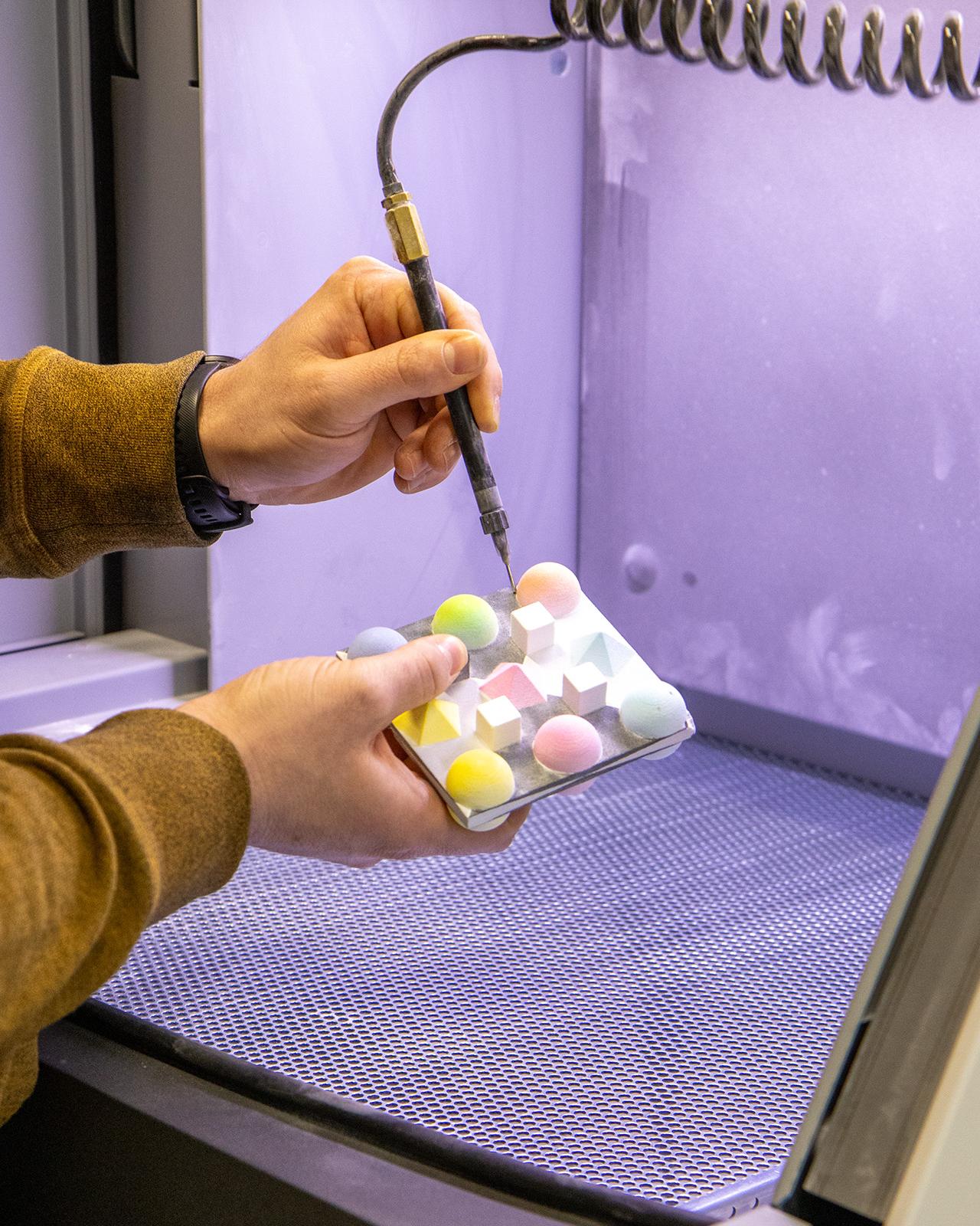 Eine Hand hält eine Art elektronische Nadel, die in bunte Kugeln sticht