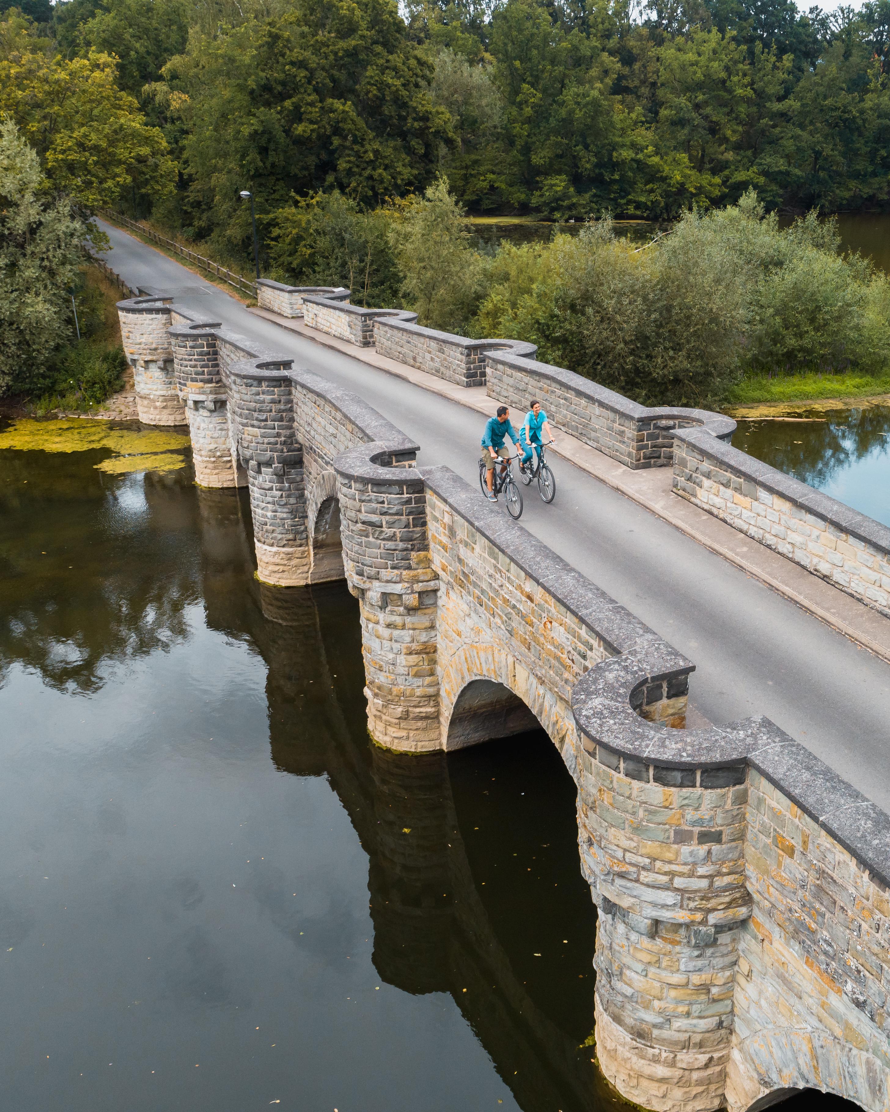 Zwei Personen fahren mit dem Fahrrad über die Kanzelbrücke am Möhnesee