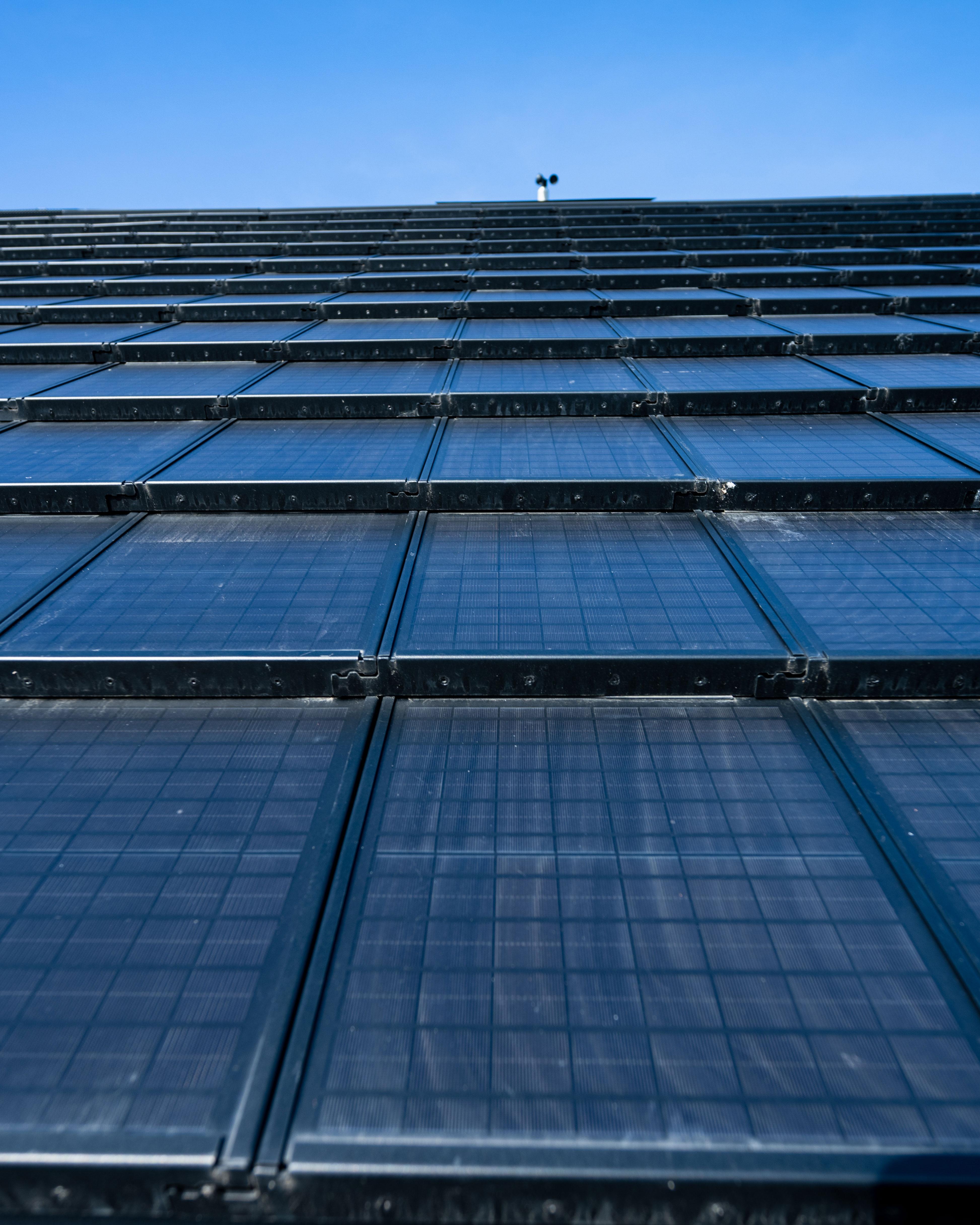 Eine mit Solarpanels gedeckte Wand ragt in einen blauen Himmel.