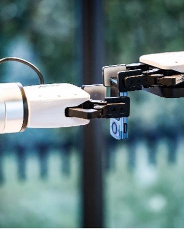 Zwei Roboterarme halten etwas gemeinsam in den Greifhänden.