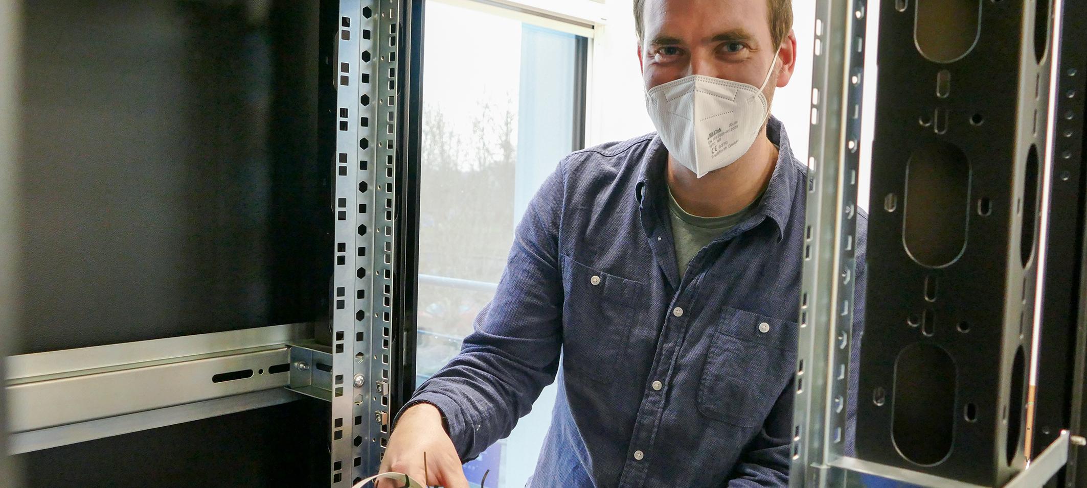 Mann mit FFP2-Maske arbeitet an elektrischen Verschaltungen